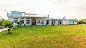 A modern two-story house with a spacious lawn, large windows, and a flat roof.