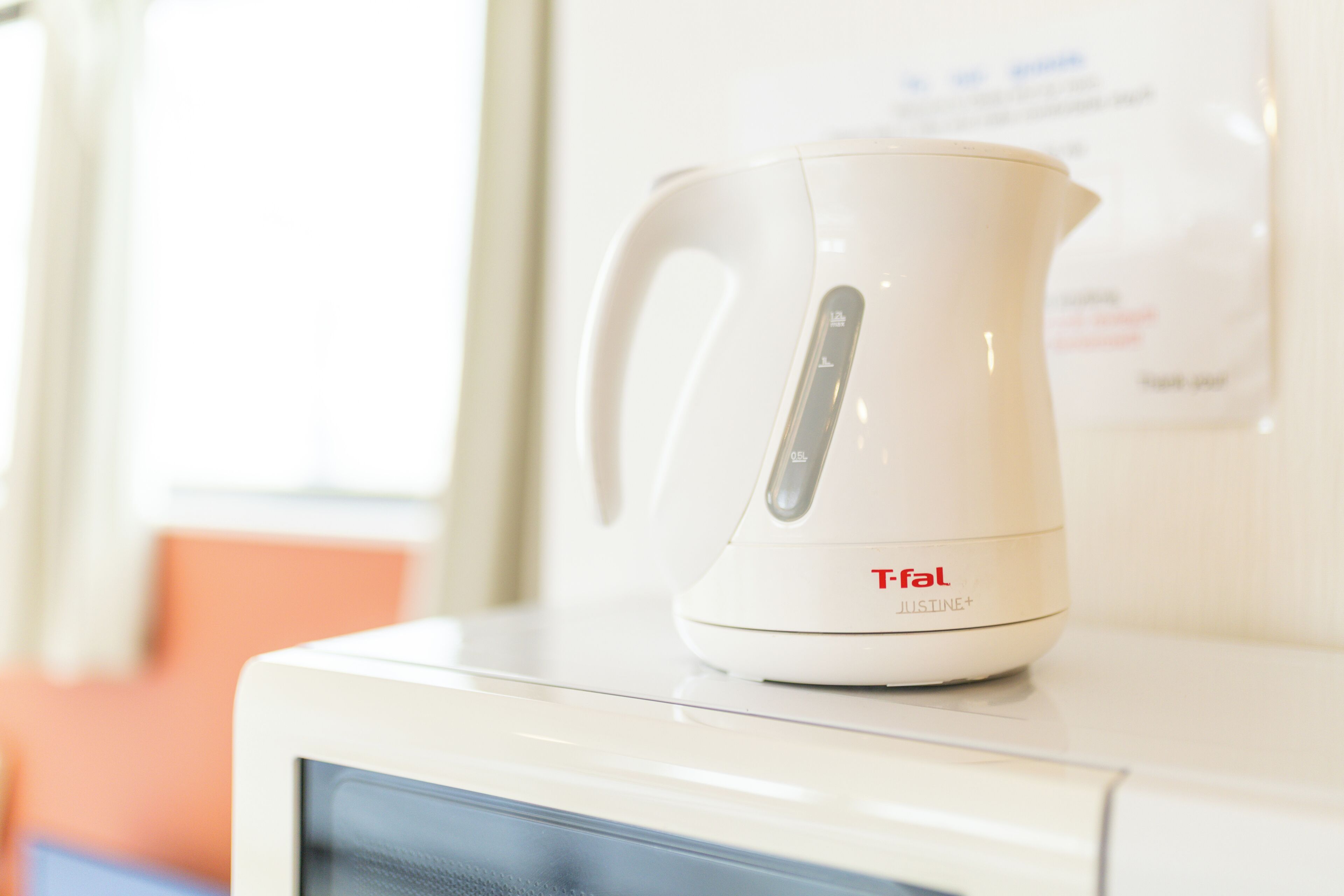 Une bouilloire électrique blanche de la marque Tefal, posée sur un four à micro-ondes.