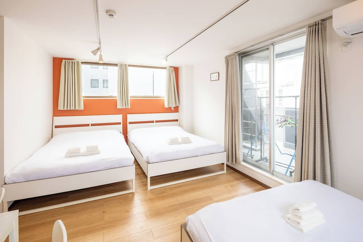 Quarto de hotel com duas camas de solteiro, uma janela grande com cortinas e vista para o exterior.