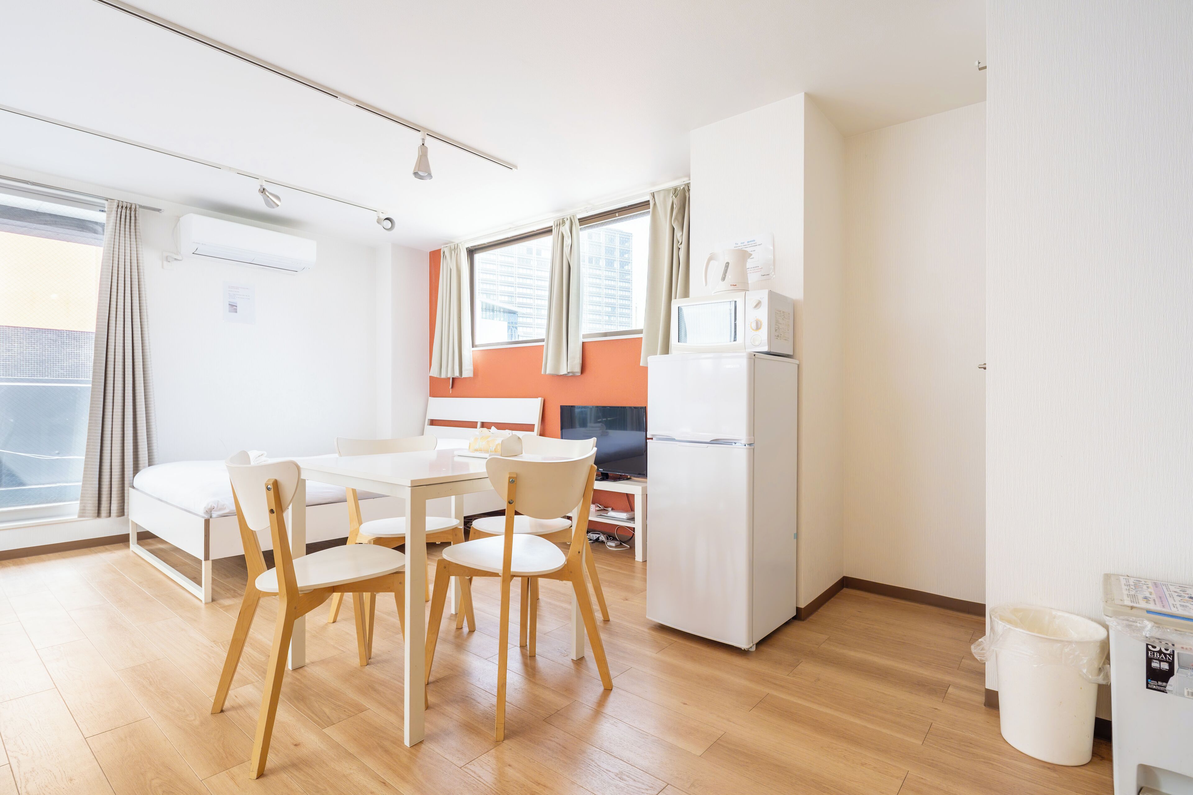 A compact kitchen with a dining table, chairs, a refrigerator, and a microwave.