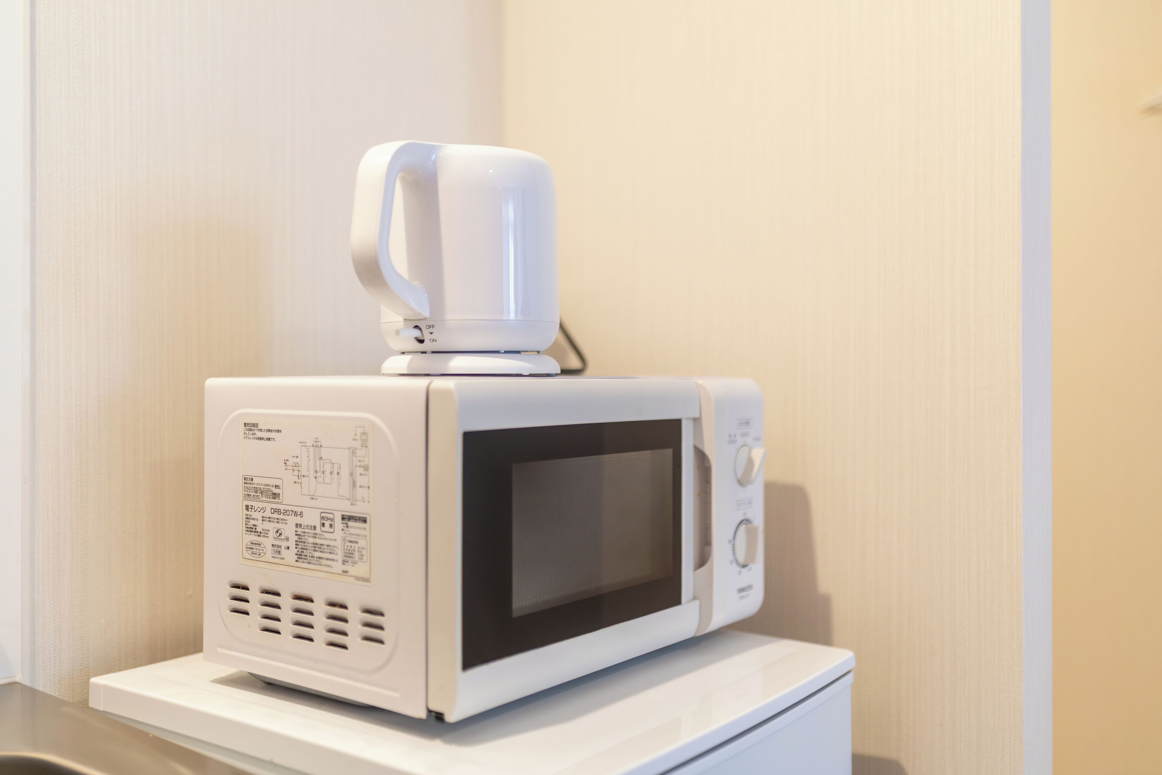 A microwave oven on a white countertop in a hotel room.