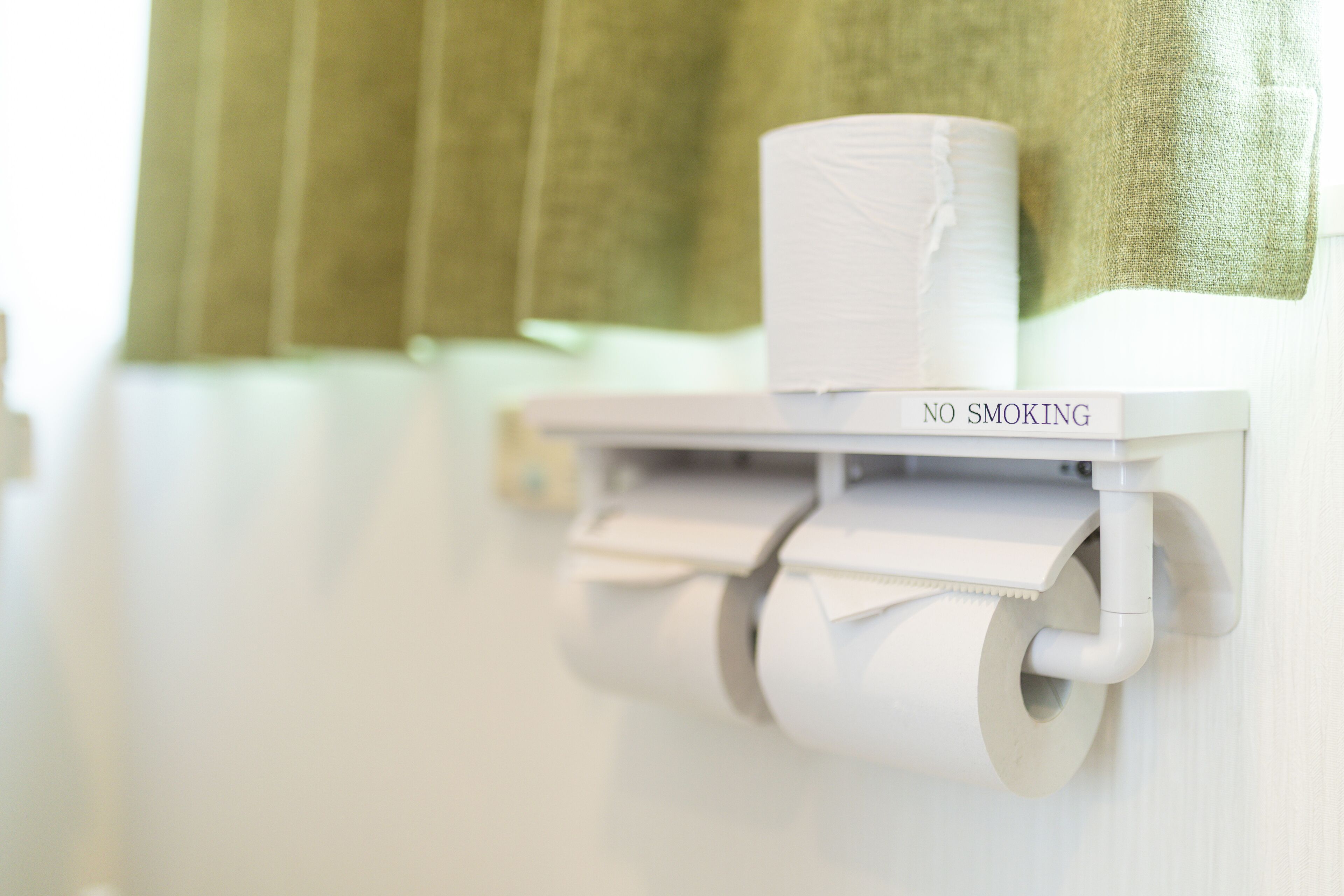 A toilet paper holder with a 'NO SMOKING' sign.