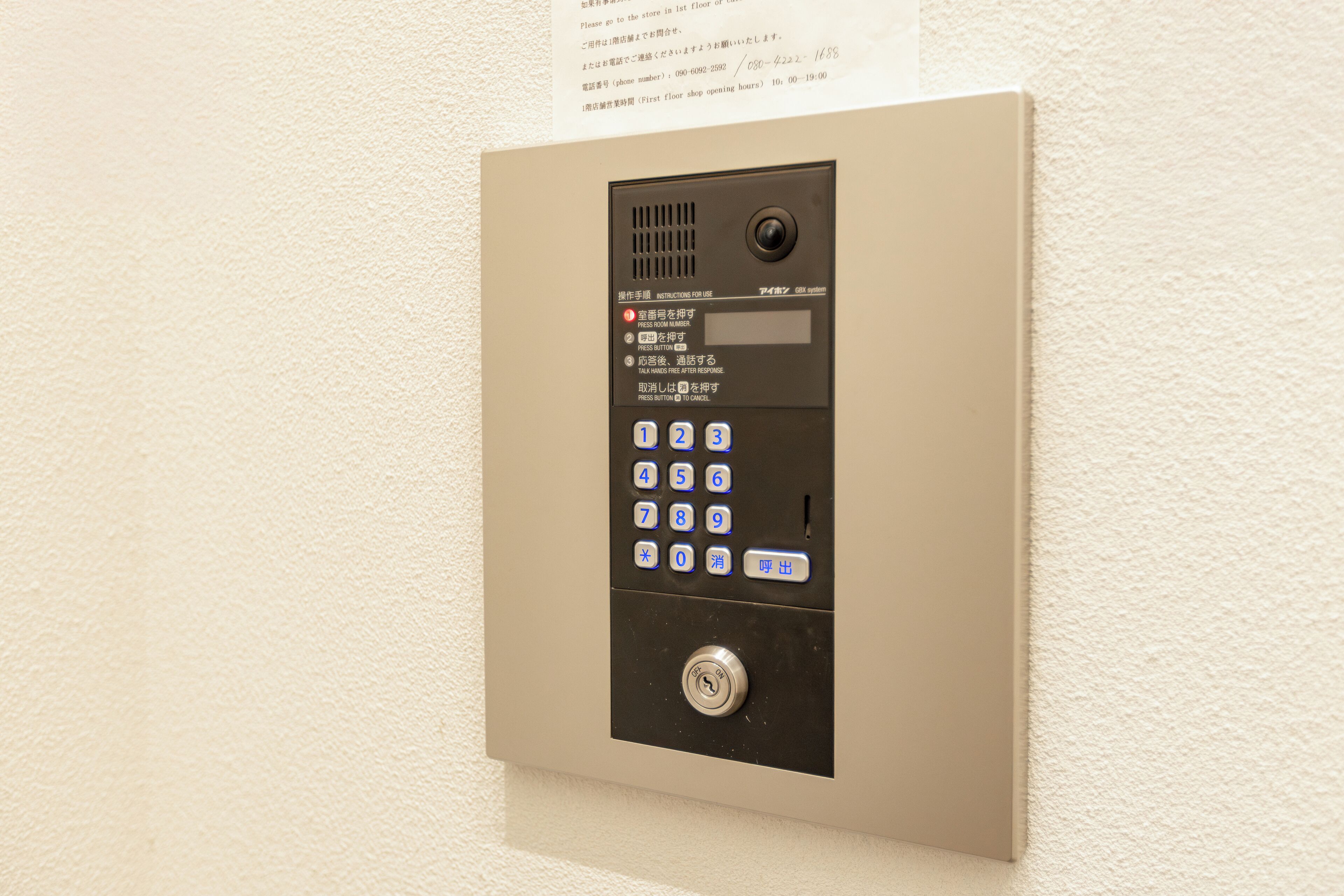A wall-mounted elevator control panel with a numeric keypad and a button.