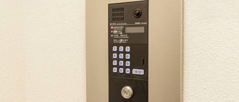 A wall-mounted elevator control panel with a numeric keypad and a button.