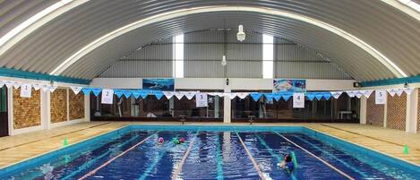 Una piscina interior con carriles, un techo abovedado alto y secciones numeradas.