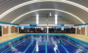An indoor swimming pool with lanes, a high arched ceiling, and numbered sections.