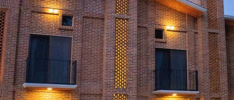 A multi-story building with a brick facade, large windows, and a central vertical feature with lights.