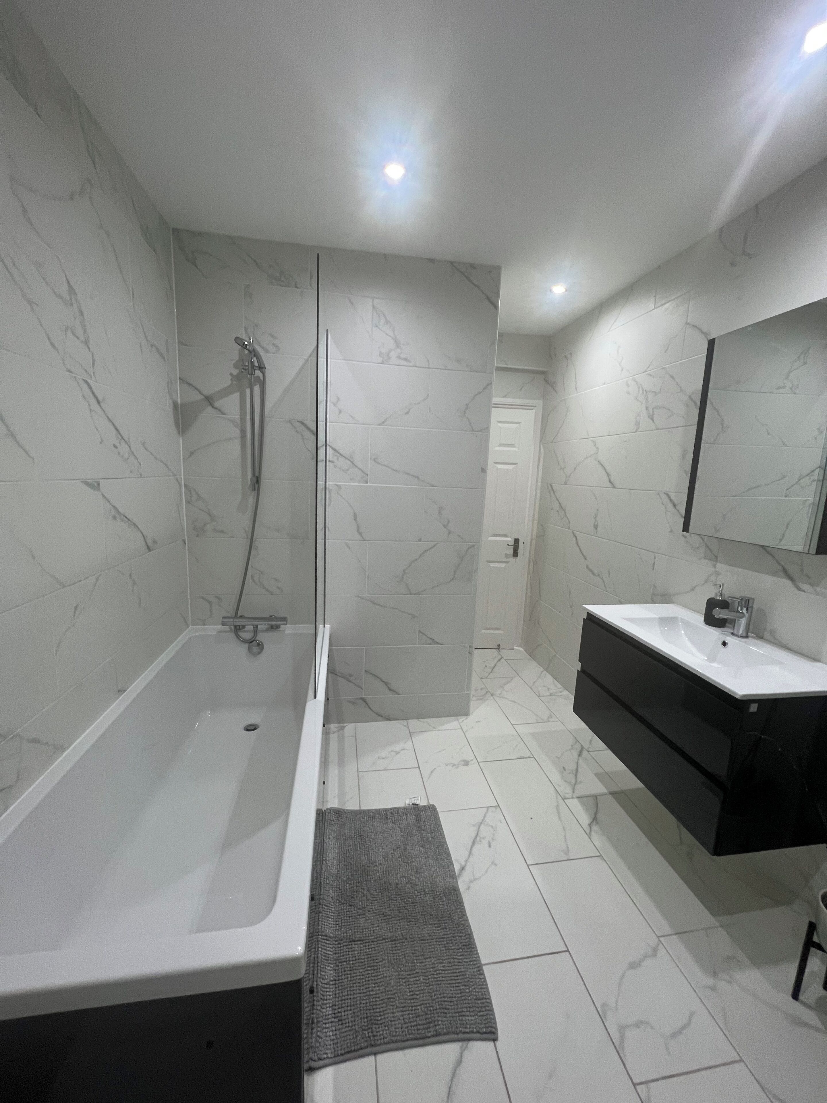 A modern bathroom with a bathtub, shower, and vanity.