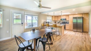 Eine moderne Küche mit Holzschränken, einem Edelstahlkühlschrank und einem Essbereich mit Holztisch und -stühlen.