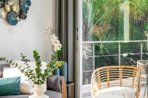 Ein modernes Wohnzimmer mit einer Couch, Wanddekoration und Blick auf einen üppigen Garten durch eine Glastür.