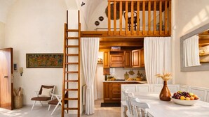 Una cocina acogedora con armarios de madera, una mesa de comedor con sillas, y un dormitorio en un altillo.