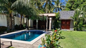 A swimming pool with a tiled edge, surrounded by a grassy lawn and palm trees. - Rancho de 3 dormitorios en la Costa del Sol, La Paz. con aire acondicionado (El zapote)