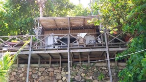 Una estructura de madera rústica con base de piedra, que cuenta con un balcón y un techo de paja.