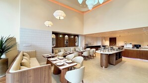 A modern dining area with booths and tables, a bar area, and a kitchen in the background. - Peace Home Boutique Hotel (Phu Thuy)