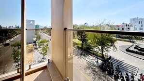 A balcony with a view of a cityscape, including buildings and a road. - Peace Home Boutique Hotel (Phu Thuy)