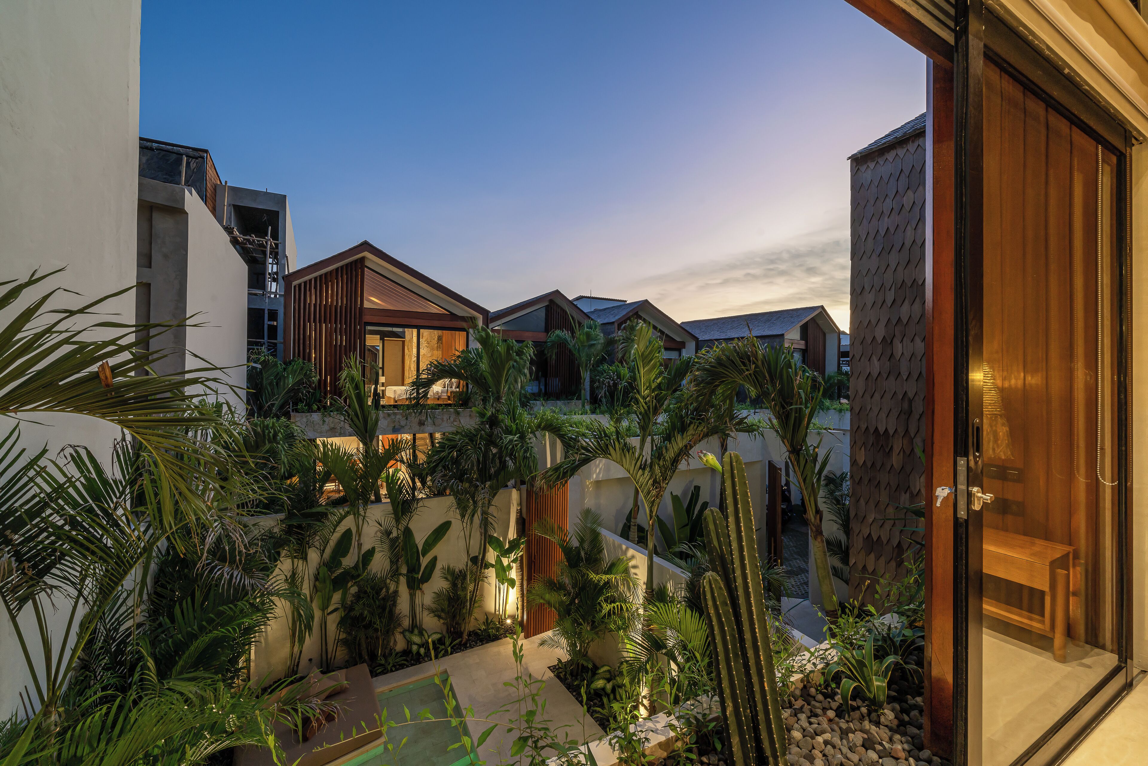 Un moderno resort con varias villas, exuberantes jardines tropicales y una zona de piscina.