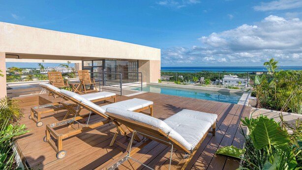 Ein Poolbereich auf dem Dach mit Liegestühlen und Blick aufs Meer.