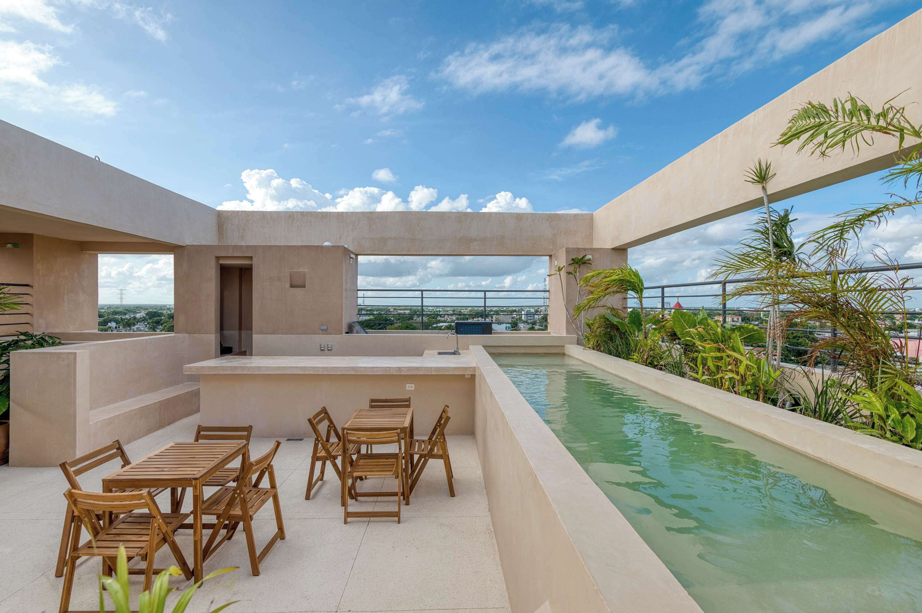 Une terrasse sur le toit avec une piscine, des meubles en bois et une vue sur le paysage urbain.