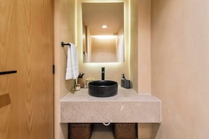 A modern bathroom with a round sink, a mirror, and a towel rack. - Nalú: Loft with private patio near the beach (Playa del Carmen)