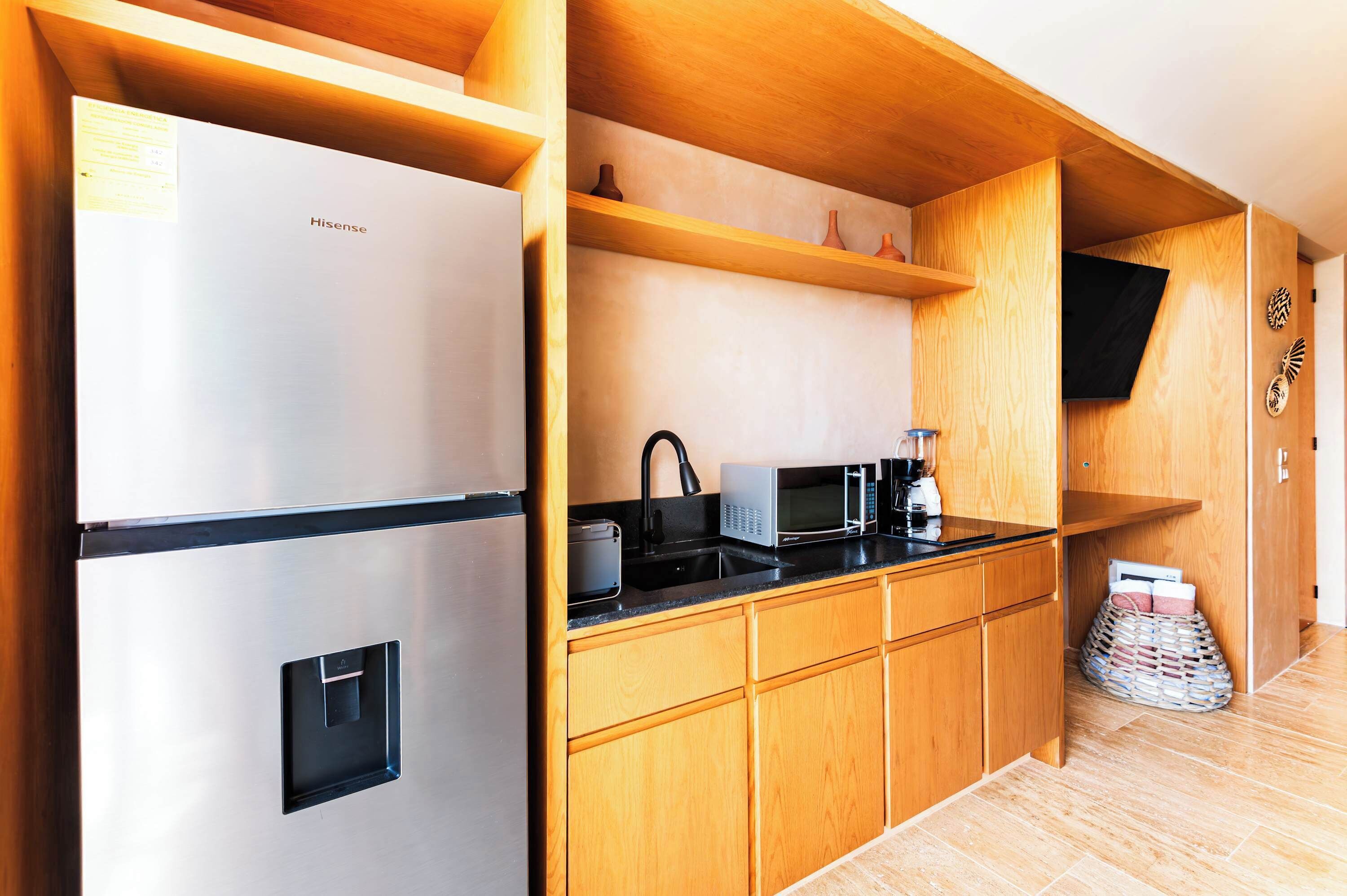A compact kitchen with a stainless steel refrigerator, a microwave, and a sink.