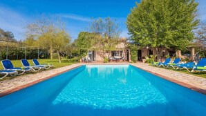 A rectangular swimming pool with clear blue water, surrounded by blue lounge chairs and a small gazebo. - MIRABO - Villa with private pool and free WiFi (Manacor)