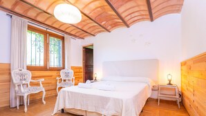 A bedroom with a large bed, two chairs, a nightstand, and a window with curtains. - MIRABO - Villa with private pool and free WiFi (Manacor)