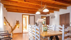 A dining area with a wooden table and white chairs, a chandelier, and a wooden ceiling. - MIRABO - Villa with private pool and free WiFi (Manacor)