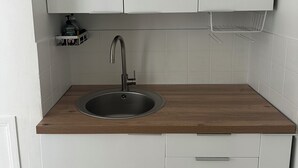 A kitchen with a wooden countertop, a stainless steel sink, and white cabinets.