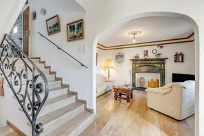 A staircase with ornate metal railings, a living room with a sofa and a fireplace, and a hallway with a door leading to another room. - Casa Naima (Alto Malcantone)