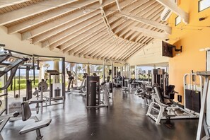 Ein Fitnessstudio mit unterschiedlichen Trainingsgeräten, einer Holzbalkendecke und großen Fenstern.