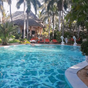 A swimming pool with lounge chairs and palm trees. - African House Resort Malindi (Malindi)