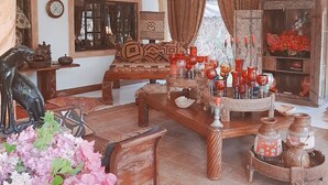 A traditional room with a wooden sofa, a decorative table with red vases, and a large mirror. - African House Resort Malindi (Malindi)