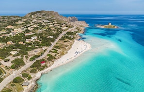 An aerial view of a coastal area with a beach, a small island, and a town with buildings and roads. - Stunning home in Stintino with WiFi (Stintino)
