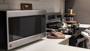 A kitchen with a microwave, kettle, and a shelf with jars. - Enjoy a stylish, comfort, space experience in this beautiful maintained home. (Baton Rouge)