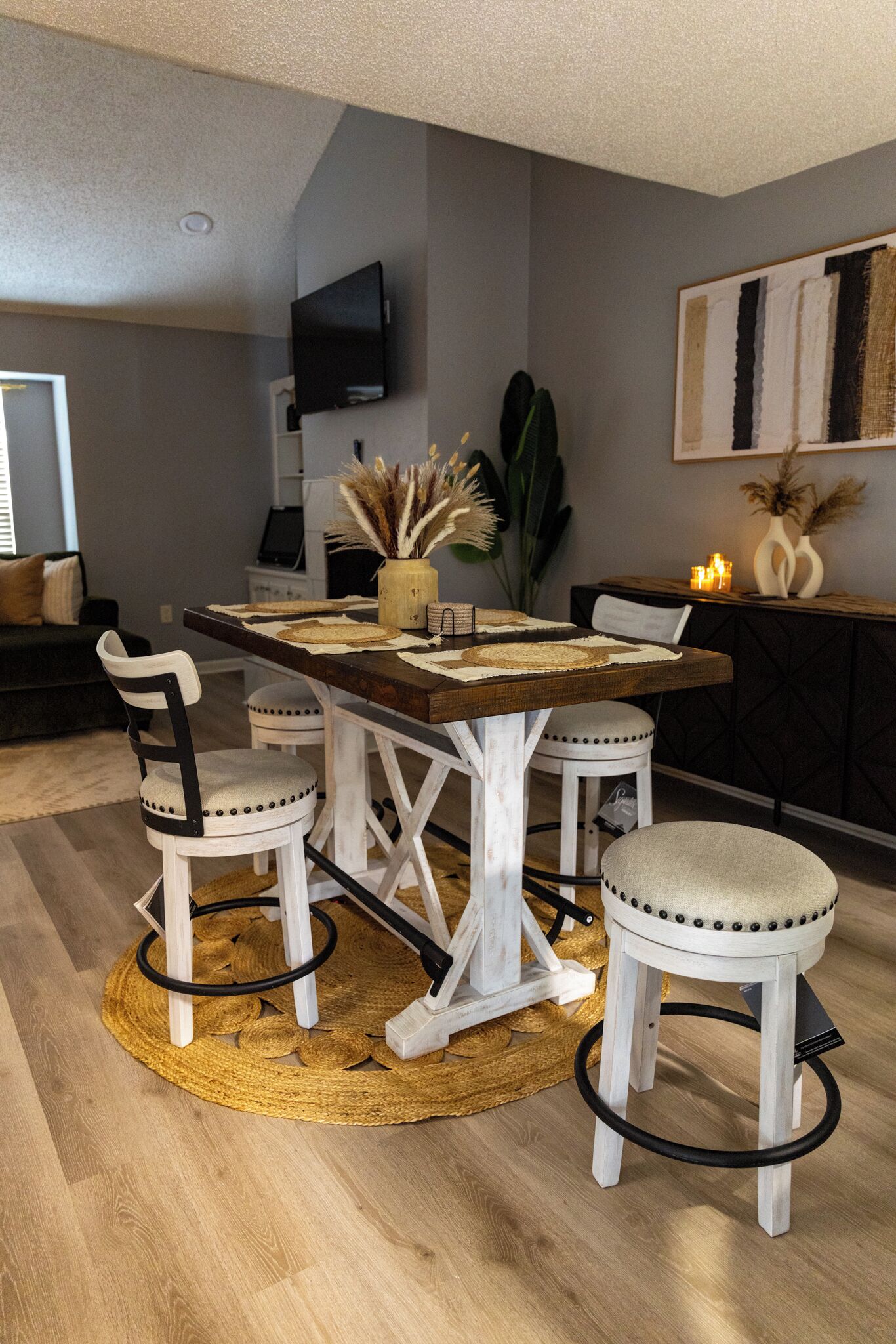 A dining area with a wooden table, white chairs, and a woven rug.