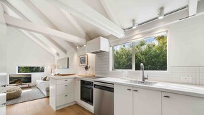 Una cocina moderna con armarios blancos, un ventanal grande y un horno empotrado.