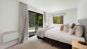 Un dormitorio con una cama grande, una ventana con vistas a zonas verdes y un ventanal corredero que da a un espacio exterior.