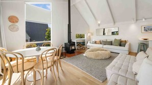 Una sala de estar moderna con comedor, chimenea, sofá y un ventanal grande.