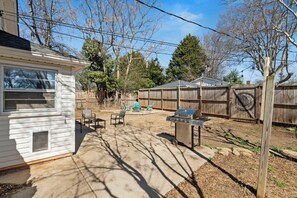 A backyard with a barbecue grill, patio furniture, and a wooden fence.