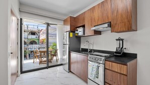 A modern kitchen with wooden cabinets, a built-in oven, and a blender on the counter. - Unit Pepinillo Romantic Zone (Puerto Vallarta)