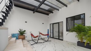 A modern interior with a staircase, a hammock, and a large potted plant. - Unit Pepinillo Romantic Zone (Puerto Vallarta)