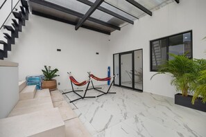 A modern interior with a staircase, a hammock, and a large potted plant. - Unit Pepinillo Romantic Zone (Puerto Vallarta)