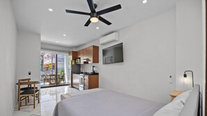 A modern bedroom with a bed, a ceiling fan, and a TV mounted on the wall. - Unit Pepinillo Romantic Zone (Puerto Vallarta)