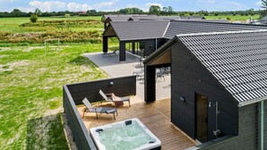 Ett modernt hus med en uteplats, utomhusmöbler och en bubbelpool.