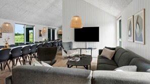 Ett rymligt rum med en matplats, en soffa, en tv och konstverk på väggarna.