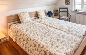 A bedroom with a wooden headboard, floral bedding, a chair, and a window with a view. - Nice home in Løgstrup with WiFi (Løgstrup)