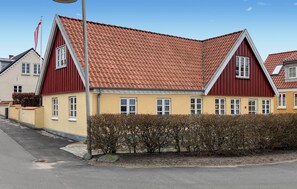 A two-story building with a red roof and yellow walls, featuring multiple windows and a flagpole. - Nice home in Løgstrup with WiFi (Løgstrup)