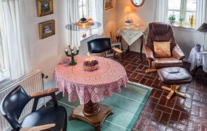A cozy dining area with a round table covered in a lace tablecloth, surrounded by leather chairs. A candelabra with candles is on the table, and a chandelier hangs above. - Nice home in Løgstrup with WiFi (Løgstrup)