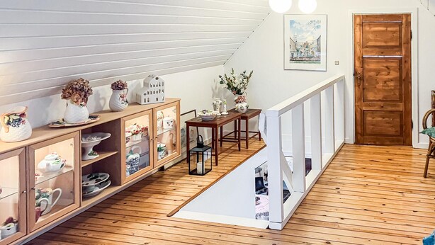 Un espace repas doté d’un plancher en bois, d’une table en bois et d’une rambarde blanche.
