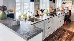 Une cuisine moderne avec des meubles blancs, un plan de travail en granit, un évier et divers ustensiles de cuisine.